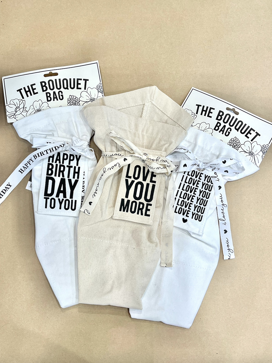 special occasion bouquet bags that say "happy birthday to you" and "love you more"